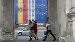 Прапори Молдови та ЄС на будинках перед якими йдуть люди 