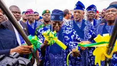 Aarẹ Bola Tinubu wọ agbada adirẹ nibi to ti ṣi papakọ ofurufu Gateway International l'Ogun, Gomina ipinlẹ Ogun, Dapo Abiodun ati Gomina tẹlẹri ipinlẹ naa, Oloye Olusegun Osoba, naa wọ iru agbada kan naa pẹlu aarẹ