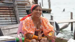 Yanisela, sentada em uma cadeira do lado de fora de sua casa em Isberyala