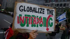 Пропалестинский участник протеста держит плакат с надписью «Глобализуй интифаду» во время антиизраильской демонстрации возле отеля премьер-министра Биньямина Нетаньяху во время 80-й сессии Генеральной Ассамблеи ООН (ГА ООН) 25 сентября 2025 года в Нью-Йорке. 