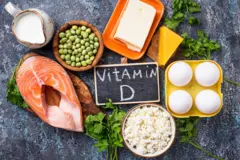somon, bezelye, yumurta, peynir gibi D vitamini kaynağı besinler siyah bir zemin üzerinde bir arada