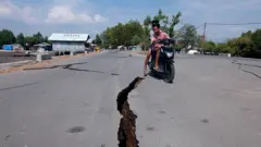 Um motociclista passa por uma rachadura na estrada após o terremoto na província de Nusa Tenggara Oriental, na Indonésia.