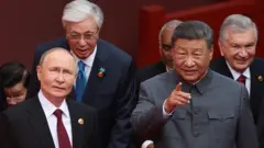ভ্লাদিমির পুতিনকে কিছু একটা আঙুল তুলে দেখাচ্ছেন শি জিনপিং, পাশে আরও চারজনকে দেখা যাচ্ছে 