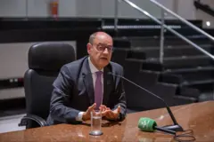 Desembargador sentado e falando em um microfone