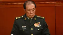 He Weidong, vestido con su uniforme militar completo, mira hacia abajo mientras está sentado en el Gran Salón del Pueblo en Pekín