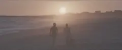 Cena do documentário Os Escolhidos da Beleza mostra duas pessoas caminhando em uma praia sob uma espécie de neblina.