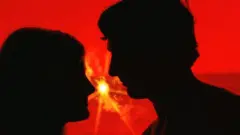 سایه نیم رخ زن و مردی با زمینه قرمز