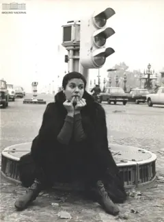 Elis sentada em rotatória com farol