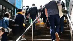 Varias personas subiendo las escaleras de un subterráneo en la ciudad.
