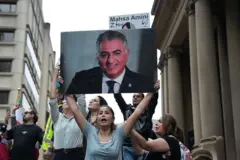 Una manifestante promonárquica iraní en Australia sostiene un retrato del heredero al trono.
