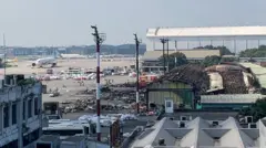 ঢাকার ঢাকার শাহজালাল আন্তর্জাতিক বিমানবন্দরের কার্গো ভিলেজে আগুন লাগার দুইদিন পর সোমবারের চিত্র। একতলা ভবনের চাল বা ছাউনি পুড়ে গেছে, সামনে পোড়া আবর্জনার স্তূপ। দূরে কয়েকটি বিমান দাঁড়িয়ে আছে