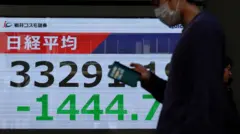 Homem caminhando em frente a um quadro mostrando o valor e a variação do índice de ações Nikkei do Japão