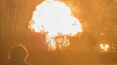 Homem observa uma bola de fogo saindo da refinaria