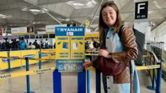 A mulher está em um aeroporto ao lado de uma estrutura de medidas de mala