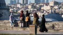 başörtülü 5 kadın istanbul silüetine bakıyor, arkaları dönük