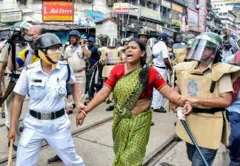 દેખાવકાર મહિલાની અટકાયત કરી રહેલી પોલીસની તસવીર 