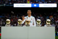 Cristiano Ronaldo mostra o número cinco com uma das mãos. Na frente dele estão cinco bolas de ouro