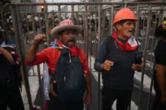 Duas pessoas gritam junto a uma grade instalada pela polícia peruana no centro da capital, Lima