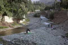 Iranianos passeiam pelo leito seco de um rio em Fasham, colocando uma esteira sobre as pedras