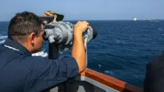 ‘번영의 수호자 작전’을 지원하며 쌍안경을 통해 홍해를 지나는 유조선을 바라보는 미 해군의 모습