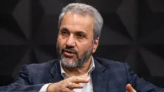 نادر یاراحمدی، با کت و شلوار و در حالیکه دستانش را تکان داده صحبت می‌کند