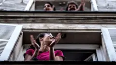 पेरिस में लोग स्वास्थ्य कर्मियों की सराहना करते हुए.