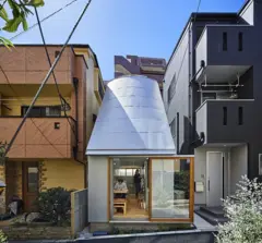 Casa espremida entre dois edifícios no meio da cidade, com teto inclinado