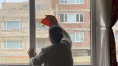 창문을 닦고 있는 한 여성의 뒷모습