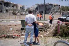 Pai e filho diante da casa destruída