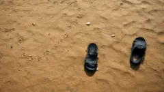 አሸዋ ውስጥ የቀረ ነጠላ ጫማ
