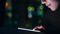 አንዲት ሴት ወደ ስልኳ አቀርቅራ እየተመለከተች