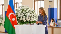 Азербайджанская избирательница бросает свой бюллетень в урну 1 сентября 2024 года