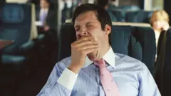 Businessman yawning on train