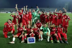 شادی بازیکنان تیم فوتبال زنان که پیراهن‌های سرخ پوشیده‌اند در زمین فوتبال