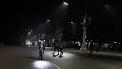 Гавана ночью: велосипедист на широкой дороге, пешеходы, минимум машин, темно