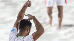 Iranian beach football player Saeed Piramoon pretends to cut his hair