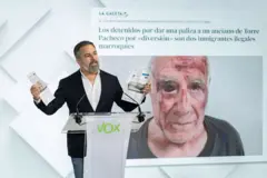 O líder do Vox, Santiago Abascal, em uma coletiva de imprensa com a imagem do idoso agredido ao fundo.