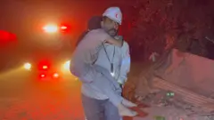 አንድ ፓራሜዲክ ሕፃን ልጅ ተሸክሞ 