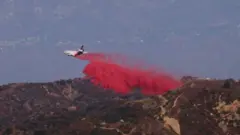 Um avião espalha poeira rosa sobre as montanhas da Califórnia
