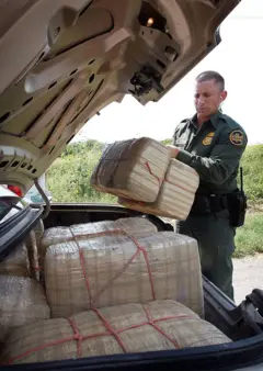 Un agente de la Patrulla Fronteriza carga paquetes de droga encontrada en el maletero de un automóvil
