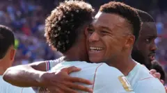 水色ユニホームのエムバペ選手がチームメートと抱き合い笑顔を見せている。近くには別の選手らがいる