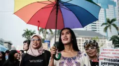 Echa Wa'ode (C), seorang aktivis dari Arus Pelangi, sebuah organisasi hak LGBTQ+ Indonesia, berbaris bersama dengan peserta lainnya selama protes yang diselenggarakan oleh Aliansi Perempuan Indonesia (API) pada Hari Perempuan Internasional ke-50 yang menuntut hak-hak buruh, kesetaraan gender dan perlindungan, di Jakarta pada 8 Maret 2025.