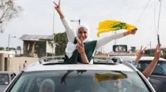 Orang-orang menunjukkan tanda kemenangan dari sebuah kendaraan ketika warga yang mengungsi kembali ke rumah mereka saat melintasi jembatan yang menghubungkan Lebanon selatan dengan bagian lain negara itu, yang sebelumnya terkena serangan Israel, setelah gencatan senjata 10 hari antara Lebanon dan Israel mulai berlaku, di Qasmiyeh, Lebanon, 17 April 2026.