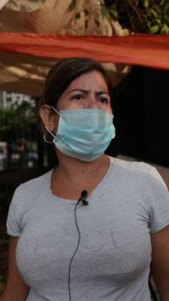 Una mujer con tapabocas y una playera gris, está en un campo de golf que alberga refugiados del terremoto en Venezuela