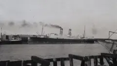 Un buque de dos chimeneas, anclado en un puerto
