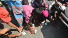 টাকা কুড়িয়ে নিতে হুড়োহুড়ি।