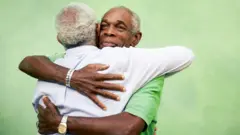 Two elderly men wey dey hug
