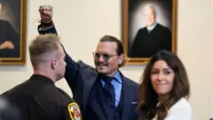 ကြားနာမှုအတွင်း တက်ရောက်လာသူတွေကို နှုတ်ဆက်နေတဲ့ ဂျွန်နီဒပ်