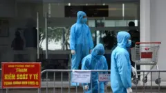 Nhân viên y tế mặc đồ bảo hộ đứng bên ngoài một tòa nhà được cách ly ở Hà Nội, Việt Nam, ngày 29 tháng 1 năm 2021