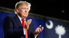 Trump mavi fonda alkış çalıyor, resmi giyimli kırmızı kravatlı 